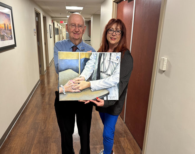 Two people holding artwork in hallway