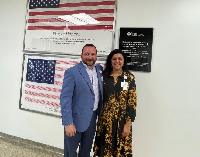 Two people standing beside memorial flag display