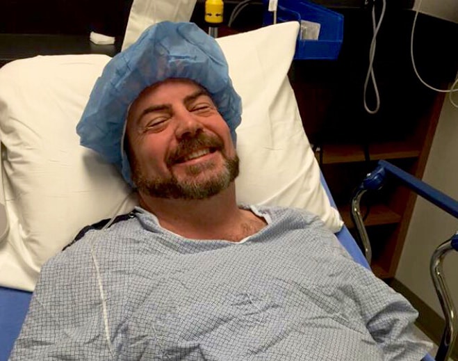 Patient resting in hospital bed wearing surgical cap