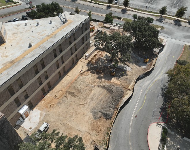 Excavation and grading work beside building