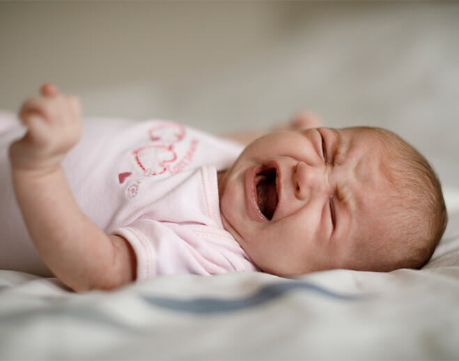 Baby lying on bed in pink clothing
