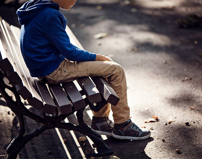 Niño sentado solo en banco del parque
