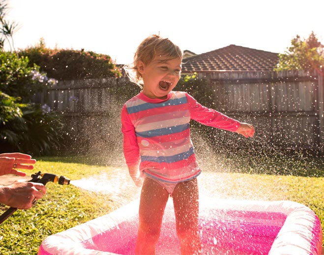Niña jugando con agua al aire libre