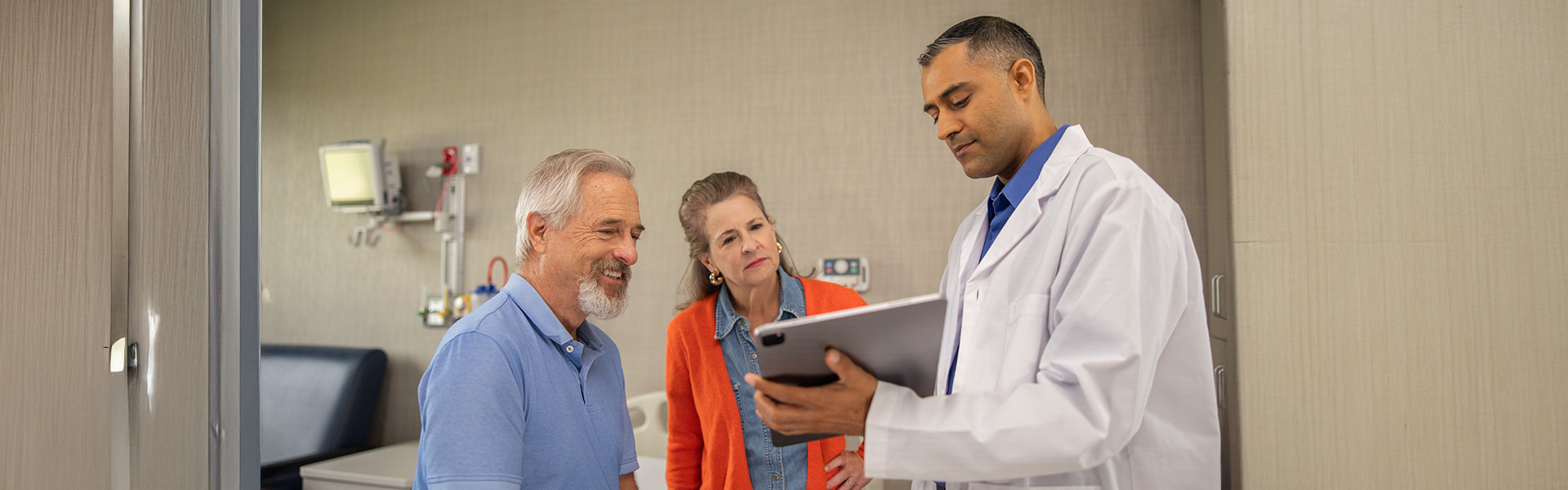 couple talking to physician, showing information on tablet