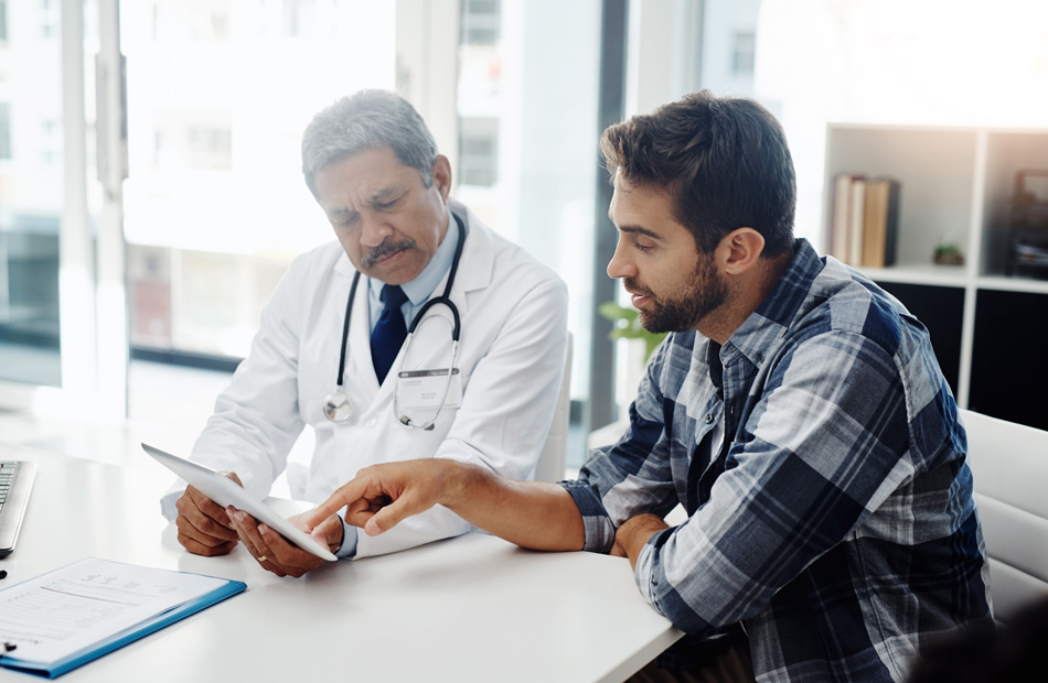 A doctor holds a tablet computer and discusses medical care options with a patient