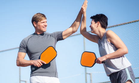 Two people high‑fiving during pickleball game