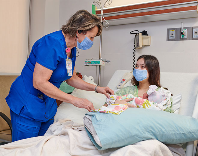 nurse-with-new-mom-and-baby-in-hospital-bed-with-masks